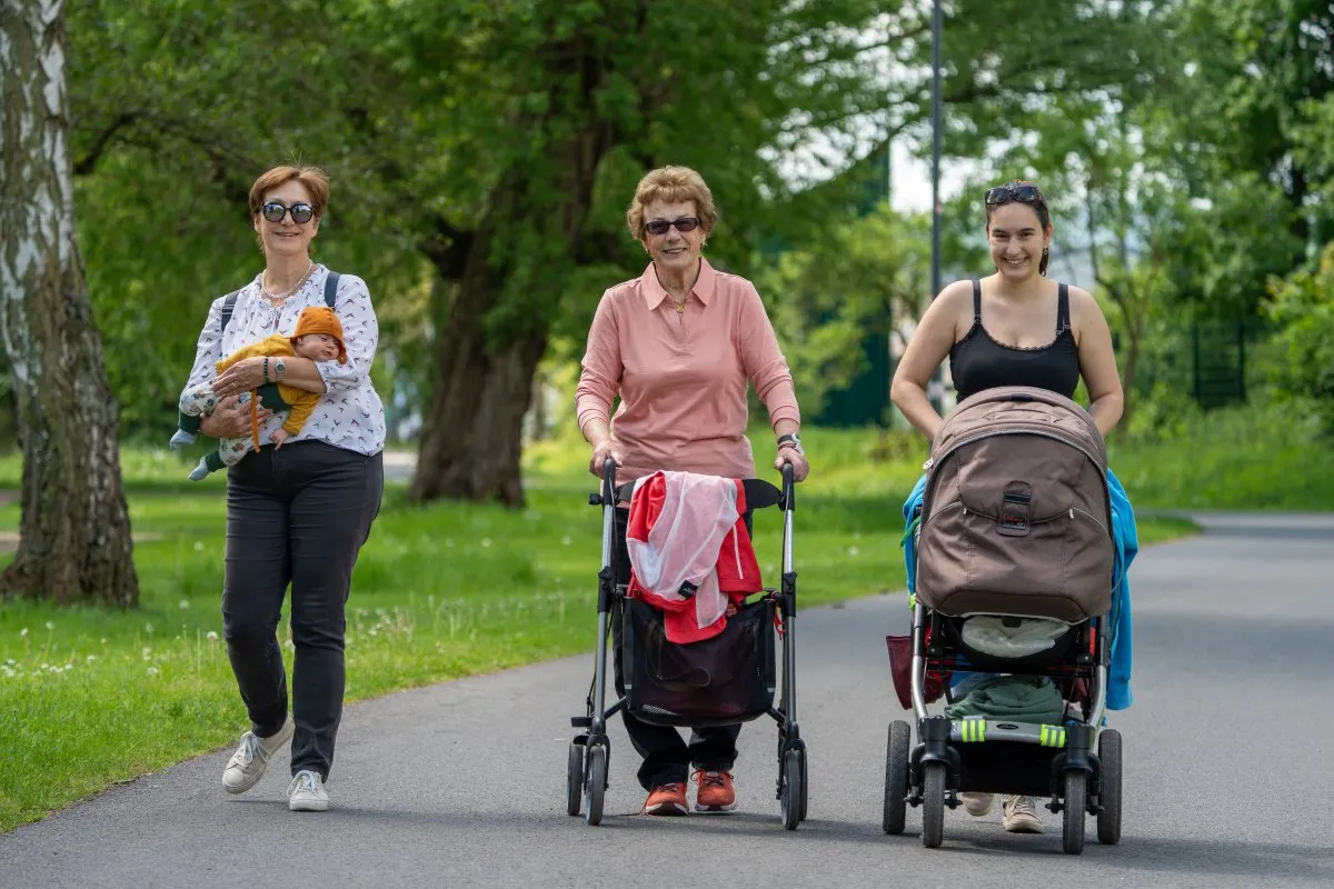 Drei Generationen unterwegs mit Kinderwagen im Park